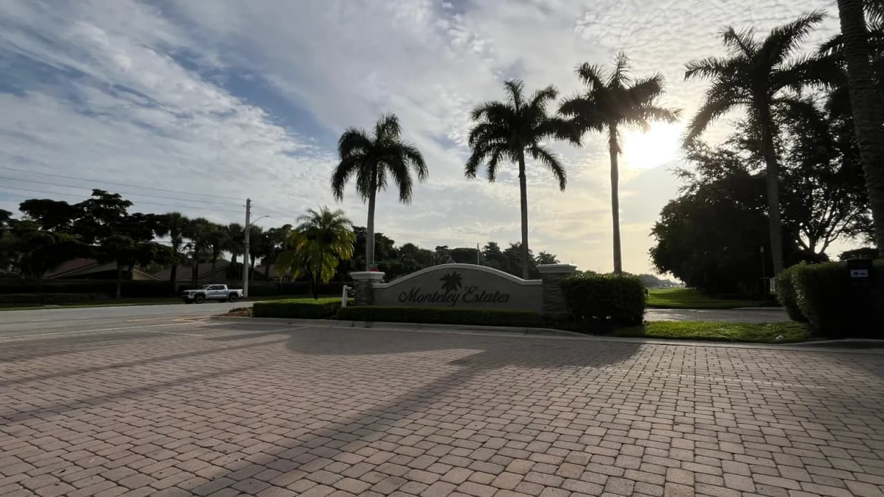 Entrance sign and palm-lined entry to Monterey Estates, a gated community in Delray Beach, Florida