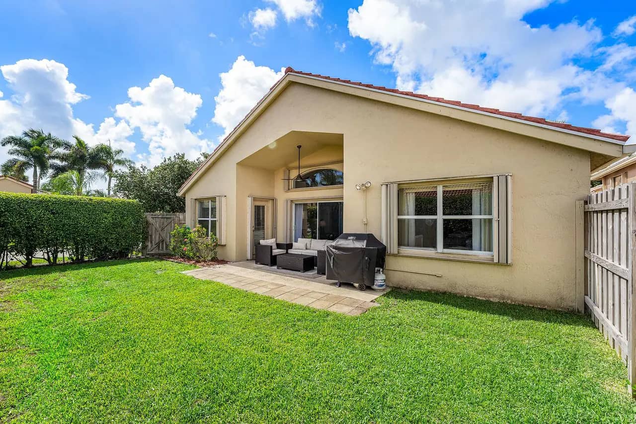 Fenced backyard at 3907 Palladium View Drive with lawn, hedge privacy screen and a covered patio