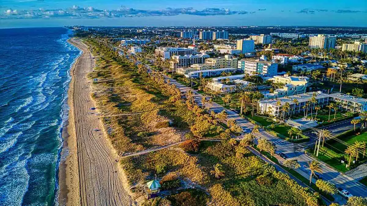 Delray Beach: compare the coastal setting with the route from your actual home. Photo: Rachel Kovalsky. Aerial view of the Delray Beach shoreline, coastal buildings and the road beside the beach.